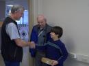 Markus Baur -- now KD0VNZ -- with his grandfather Peter Hahn, WB9KHR, receives a handheld radio from one of the Volunteer Examiners. [Joe Counsil, K0OG, Photo]