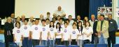 A class posing for a picture with their teachers in an auditorium.